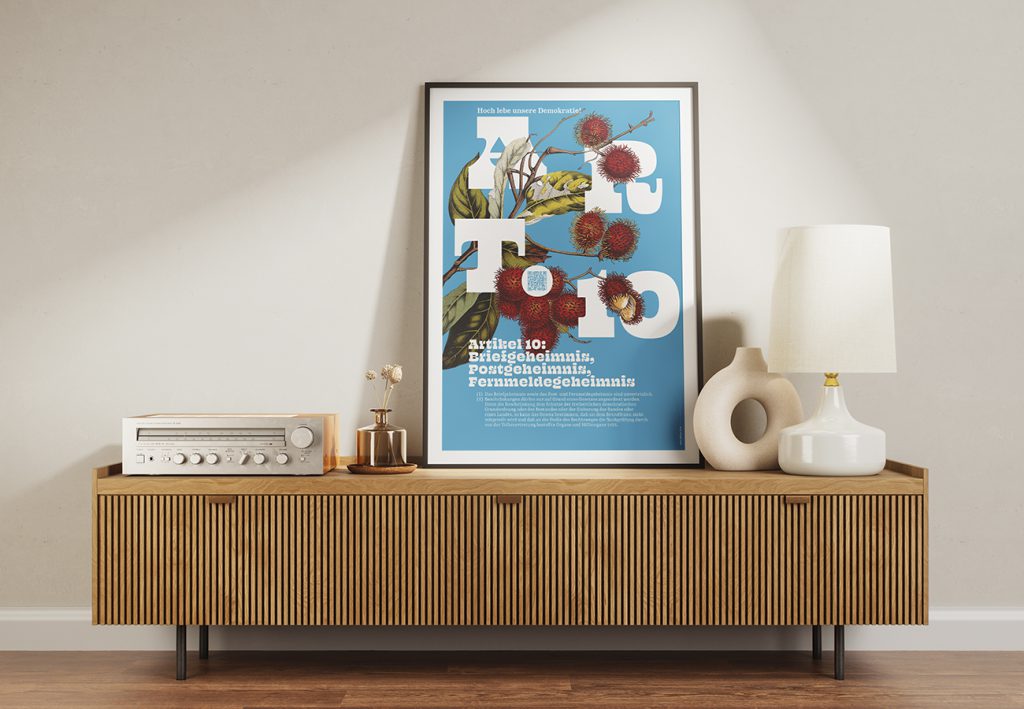 Grundrechte-Poster der Edition D zu Artikel 10 – Brief-, Post- und Fernmeldegeheimnis, blaues Motiv mit roten Früchten, gerahmt auf einem Sideboard