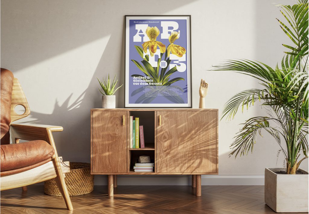 Grundrechte-Poster der Edition D zu Artikel 3 – Gleichheit vor dem Gesetz, violettes Motiv mit gelben Orchideen, gerahmt auf einem Sideboard mit Pflanze