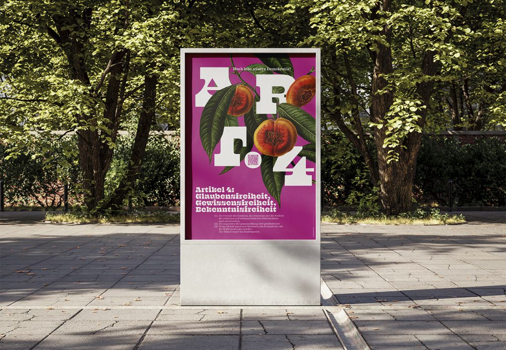 Grundrechte-Poster der Edition D zu Artikel 4 – Glaubens-, Gewissens- und Bekenntnisfreiheit, magentafarbenes Motiv mit Pfirsichzweig, in einer Stadtvitrine im Park